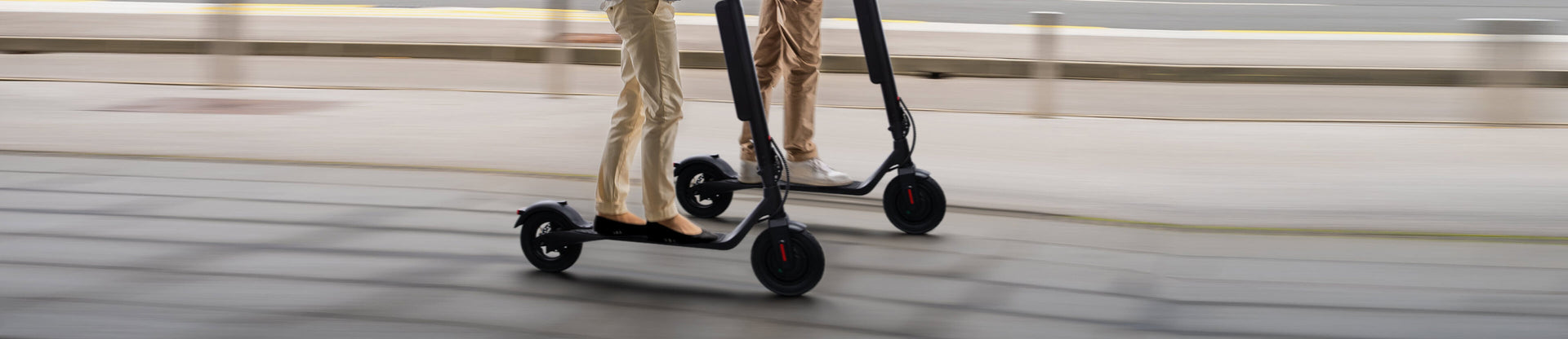 Two people riding electric scooters on a blurred background