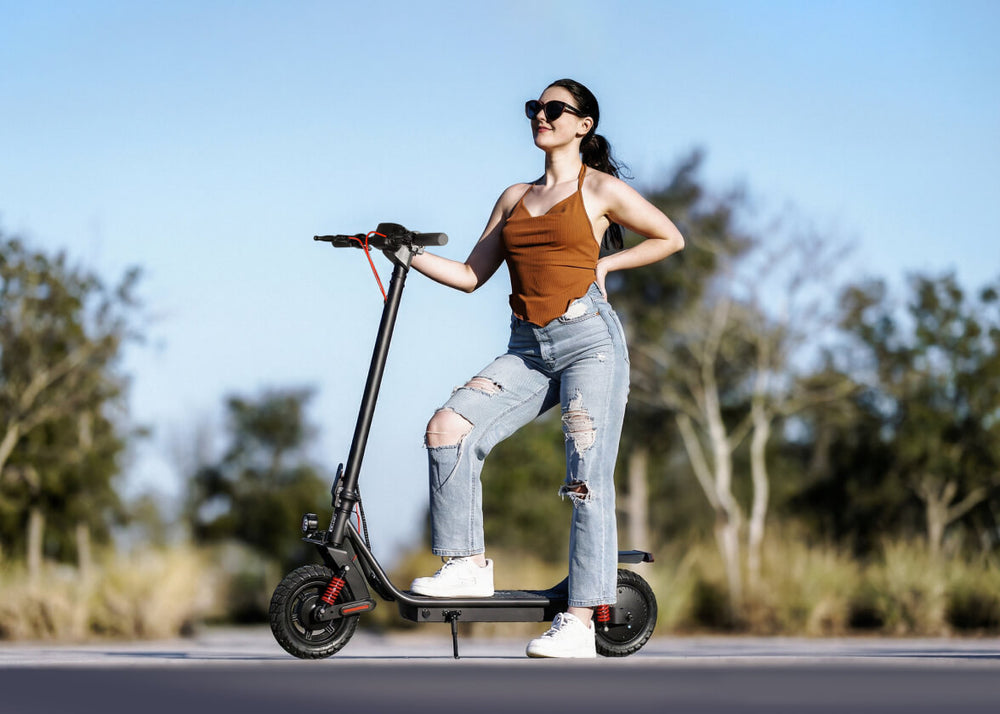 Woman riding an electric scooter on a road with trees in the background